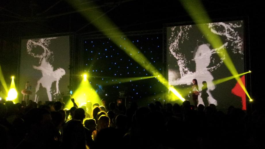 A crowd watches as interactive dancers perform, their movements creating dynamic visual effects projected in real-time via Microsoft Kinect technology.